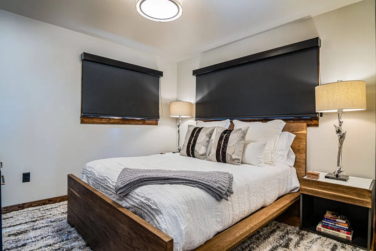 A tranquil bedroom scene showing a comfortable bed with crisp linens, decorative pillows, nightstands on either side, and soft lamp lighting. The mood is serene, inviting relaxation at any time of day.