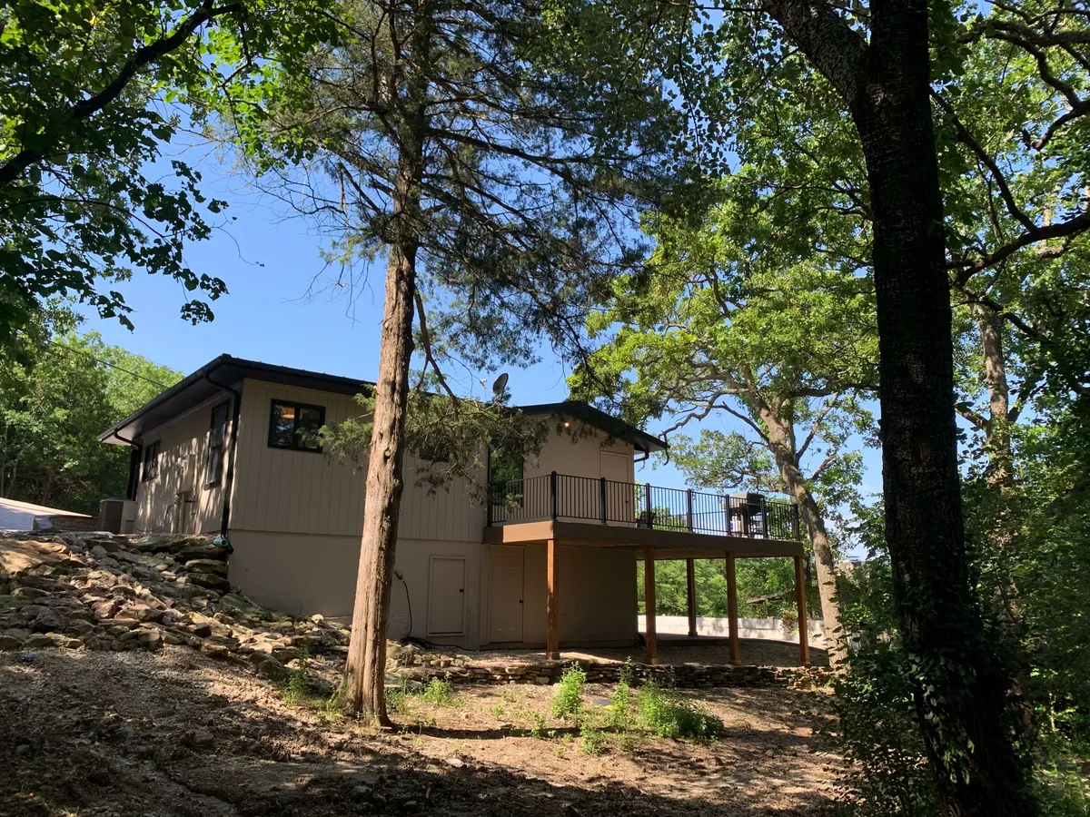 This exterior shot focuses on the home’s deck area with outdoor furniture, set against a backdrop of lush trees. The image emphasizes the seamless connection between indoor comfort and outdoor exploration, inviting guests to enjoy morning coffee or evening gatherings surrounded by nature.