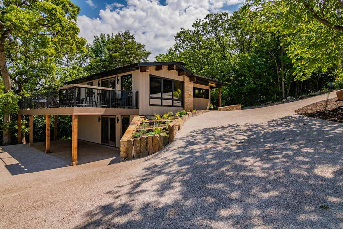 A modern home exterior with striking mid-century architecture, a spacious deck with a railing, and a beautifully landscaped garden. The orientation suggests spectacular sunset views and an inviting space for outdoor gatherings or evening relaxation.